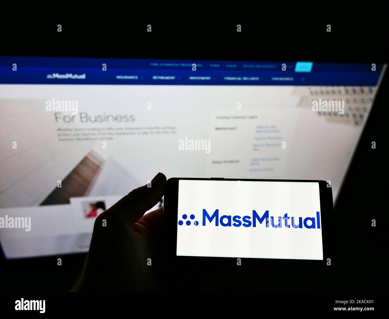 Personne tenant un téléphone portable avec le logo d'affaires de la compagnie d'assurance américaine MassMutual sur l'écran en face de la page Web. Concentrez-vous sur l'affichage du téléphone portable. Banque D'Images