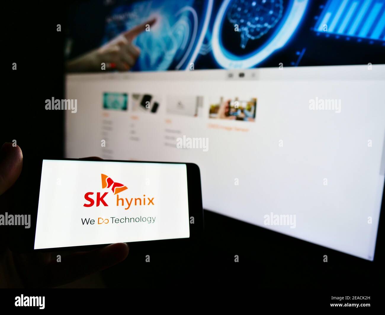 Personne tenant un téléphone cellulaire avec le logo du fabricant sud-coréen de semi-conducteurs SK hynix Inc. À l'écran en face de la page Web. Mise au point sur l'affichage du téléphone. Banque D'Images