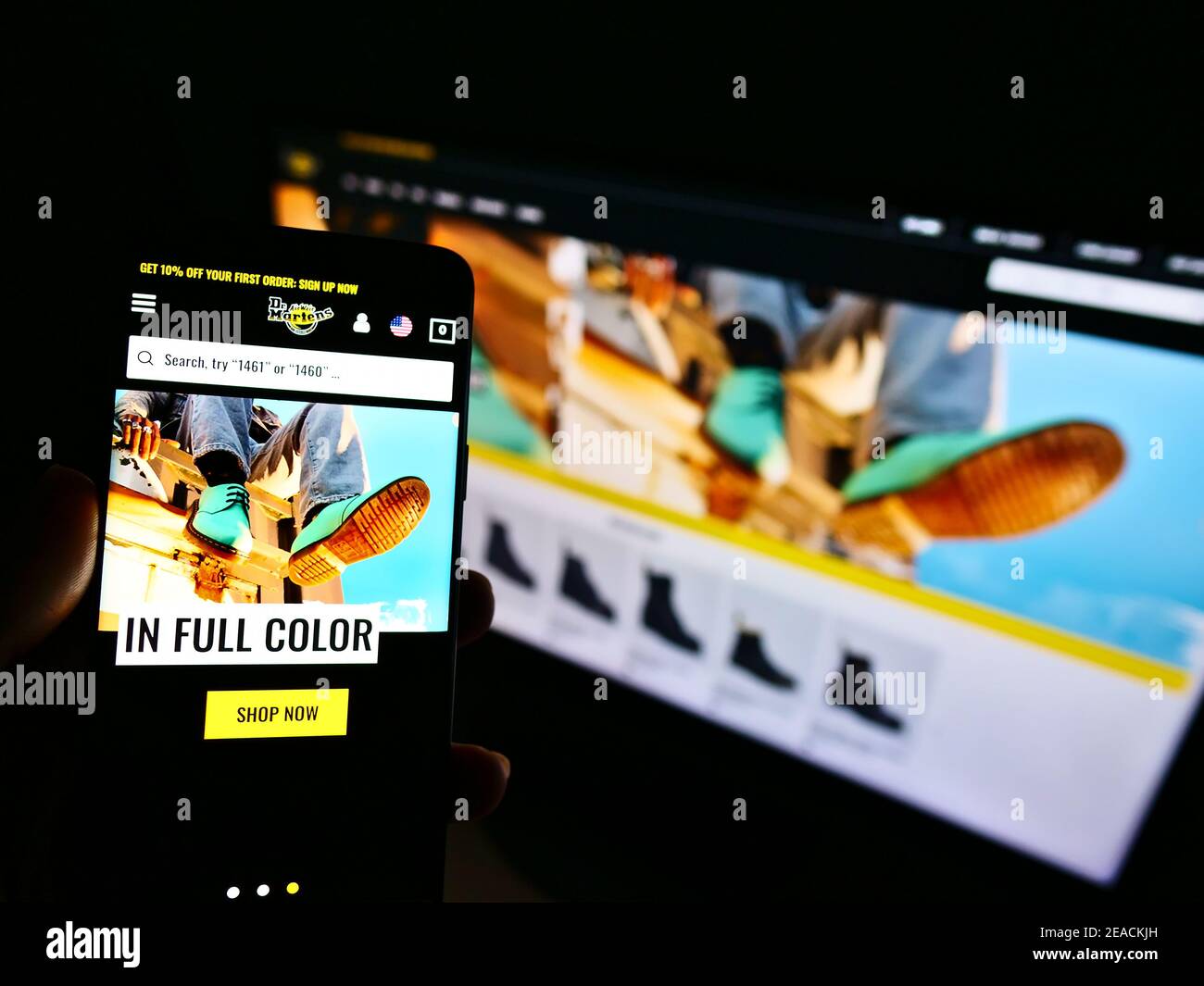 Personne tenant un smartphone avec la boutique en ligne de la marque britannique de chaussures et de vêtements Dr. Martens sur l'écran devant le site Web. Mise au point sur l'affichage du téléphone. Banque D'Images