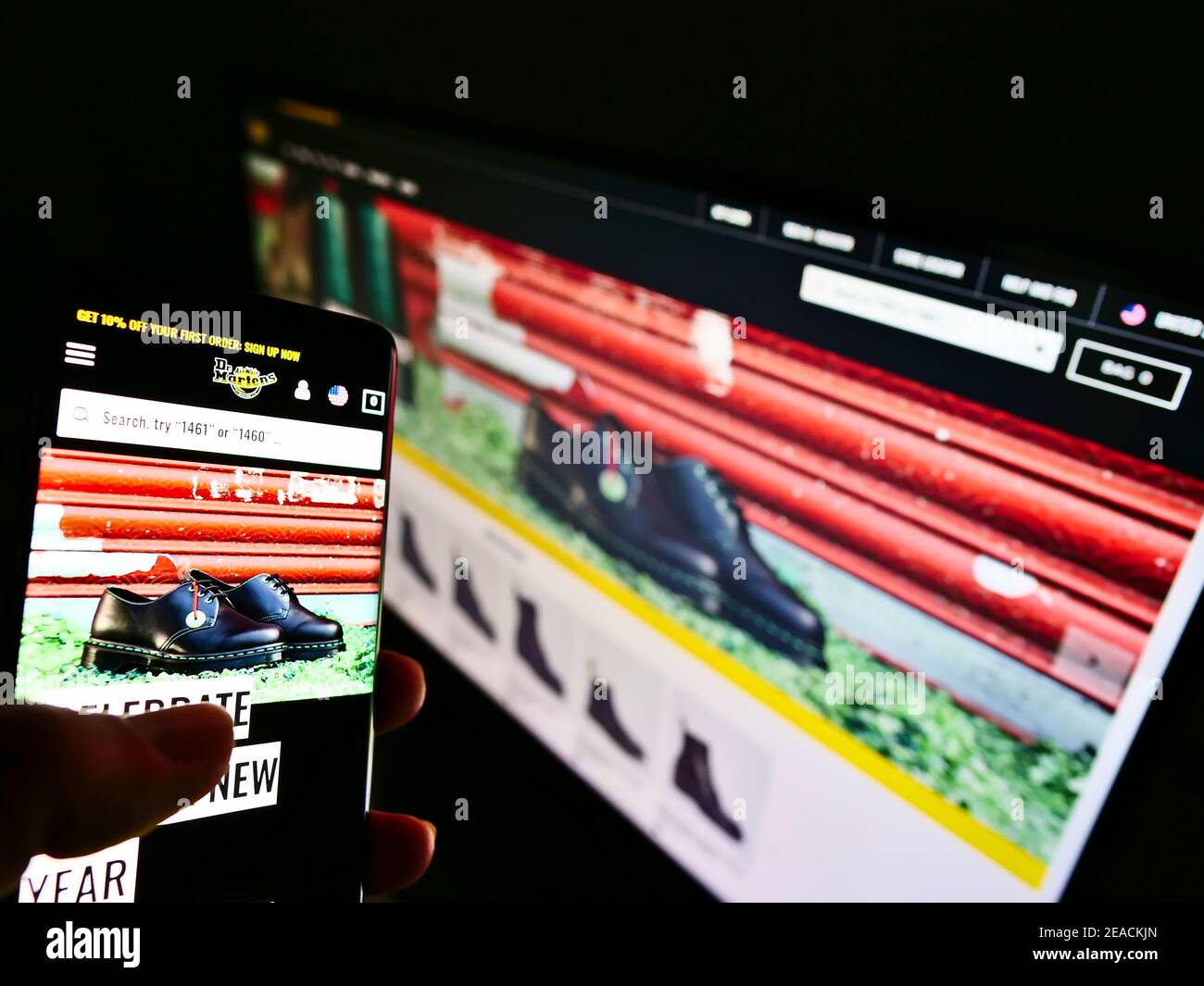 Personne défilant dans la boutique en ligne de la marque britannique de chaussures et de vêtements Dr. Martens sur l'écran de smartphone. Concentrez-vous sur le centre de l'écran du téléphone portable. Banque D'Images