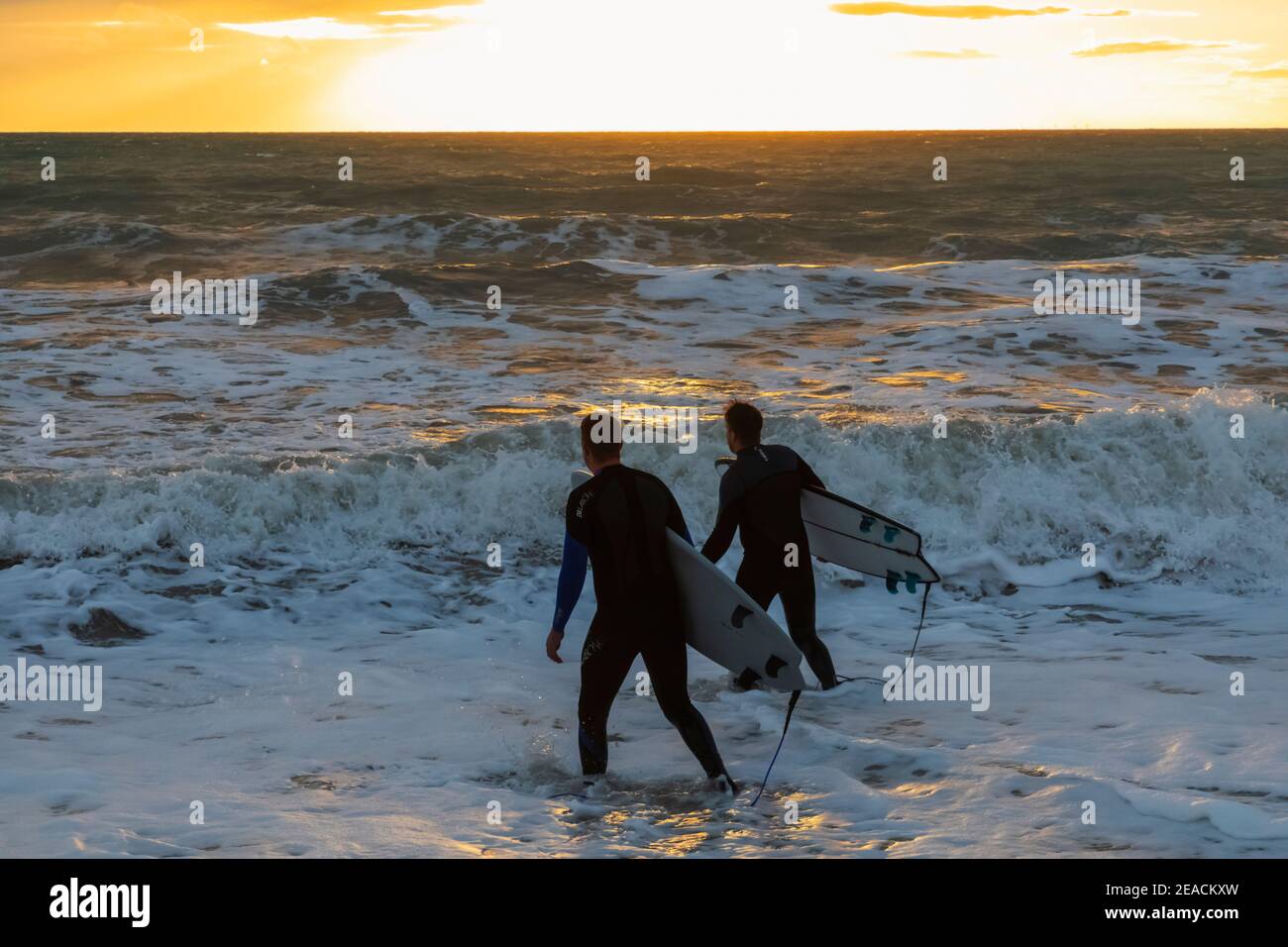 Angleterre, East Sussex, Eastbourne, Birling Gap, Seven Sisters Cliffs and Beach, Two Male Surfers Walking on Beach transportant des planches de surf Banque D'Images