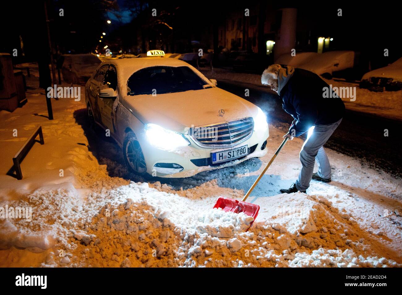 Hanovre, Allemagne. 09e février 2021. Le chauffeur de taxi Achim se déneiger devant son taxi jusqu'au bord de la route pour qu'il puisse partir. La veille, il s'est déjà coincé quatre fois avec son taxi. Credit: Hauke-Christian Dittrich/dpa/Alay Live News Credit: dpa Picture Alliance/Alay Live News Banque D'Images