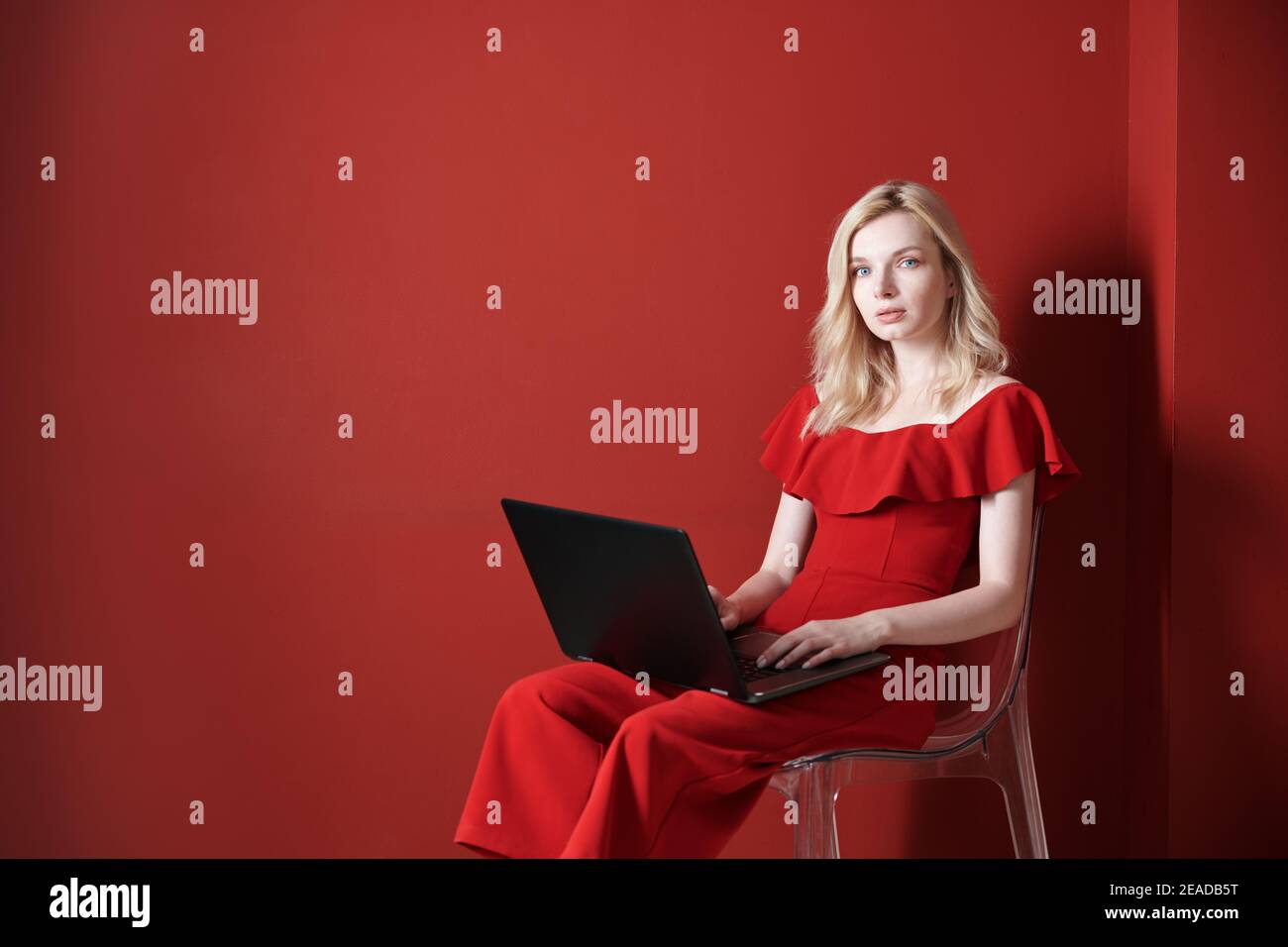 Jeune femme adulte assise sur une chaise et travaillant sur ordinateur portable Banque D'Images