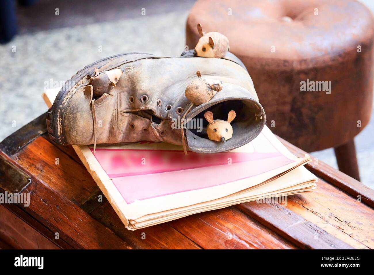 Souris en gros plan et chaussures brunes sur poitrine en bois. Souris dormant dans une vieille chaussure marron déchirée. Figurines dans le marché de rue Banque D'Images