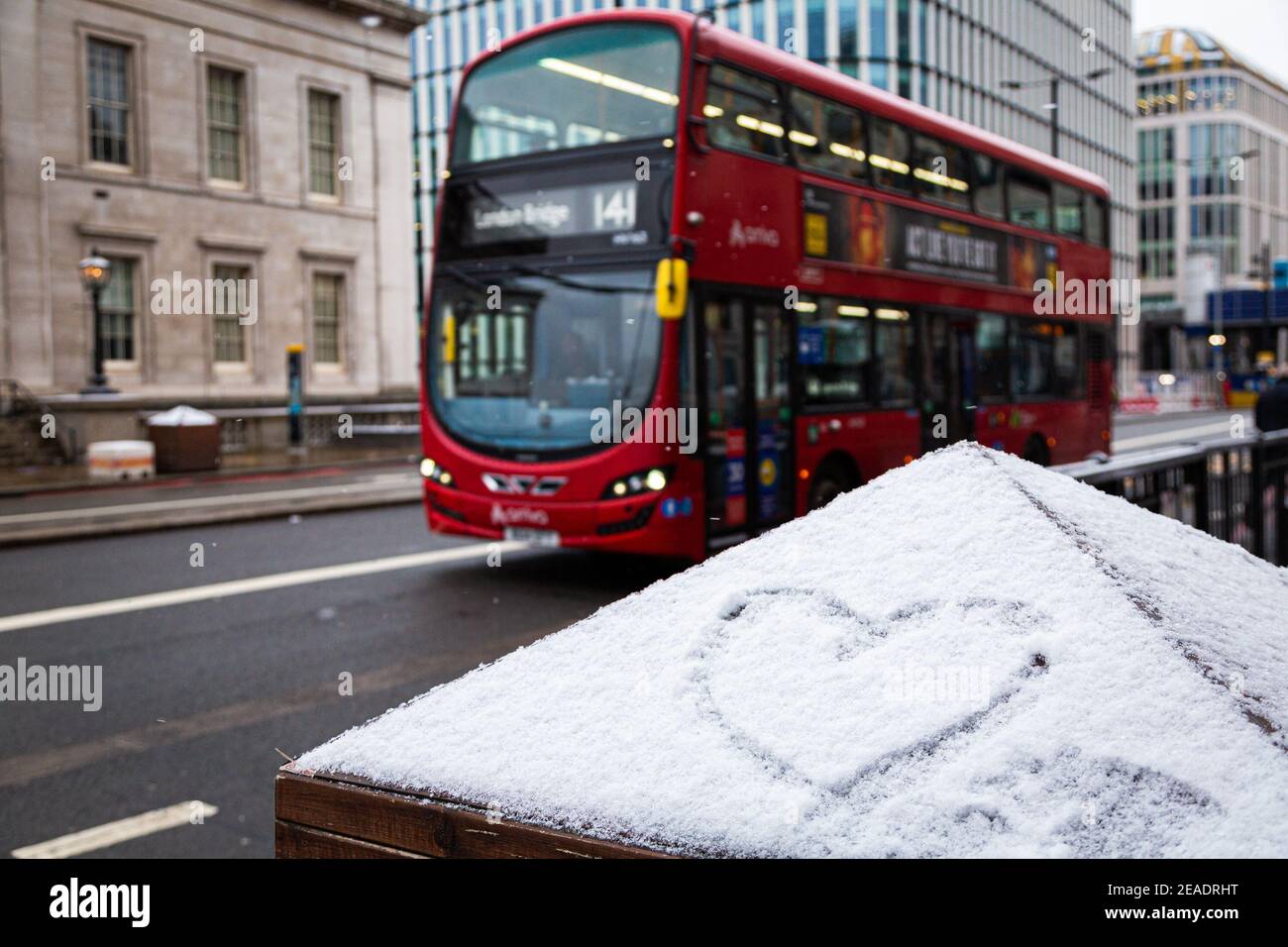 Signe d'amour en forme de coeur, dessiné sur une glace enneigée. Hiver à Londres, bus rouge. Toile de fond romantique. Forme d'un coeur sur la neige. Banque D'Images