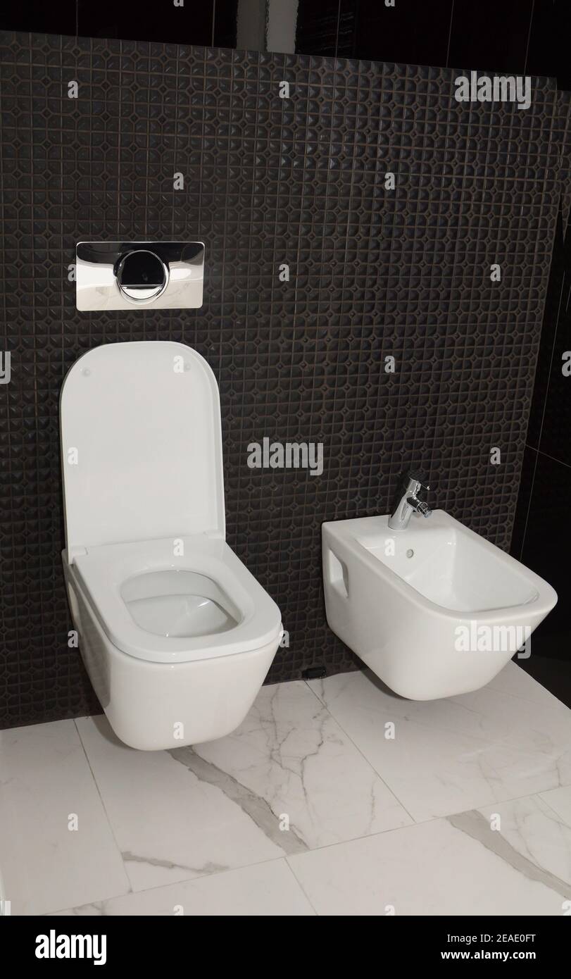 Un gros plan sur le mur des toilettes et bidet dans une salle de bains carrelée de mosaïque noire. Banque D'Images