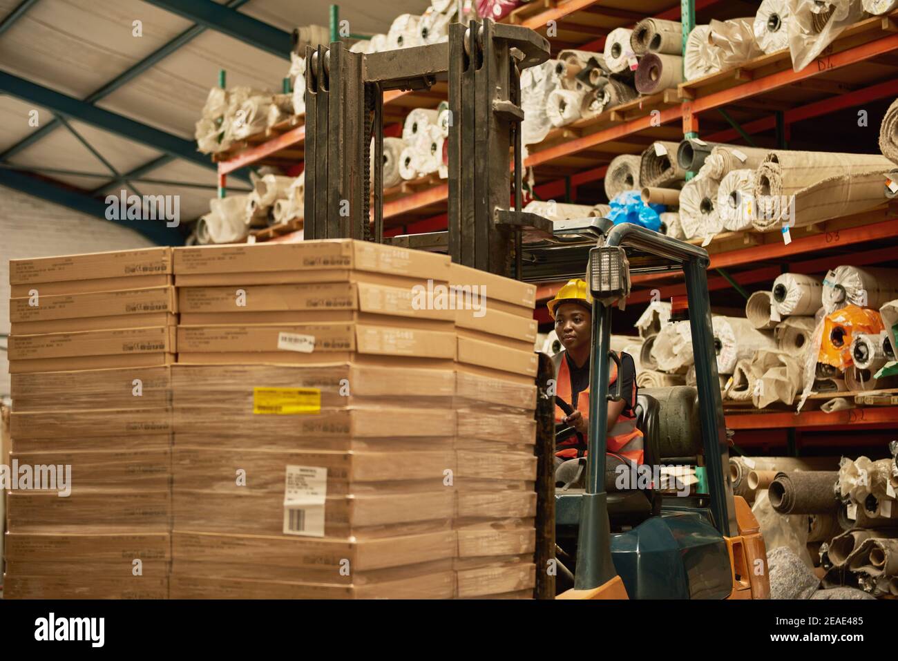 Opérateur de chariot élévateur africain mobile des palettes dans un entrepôt Banque D'Images