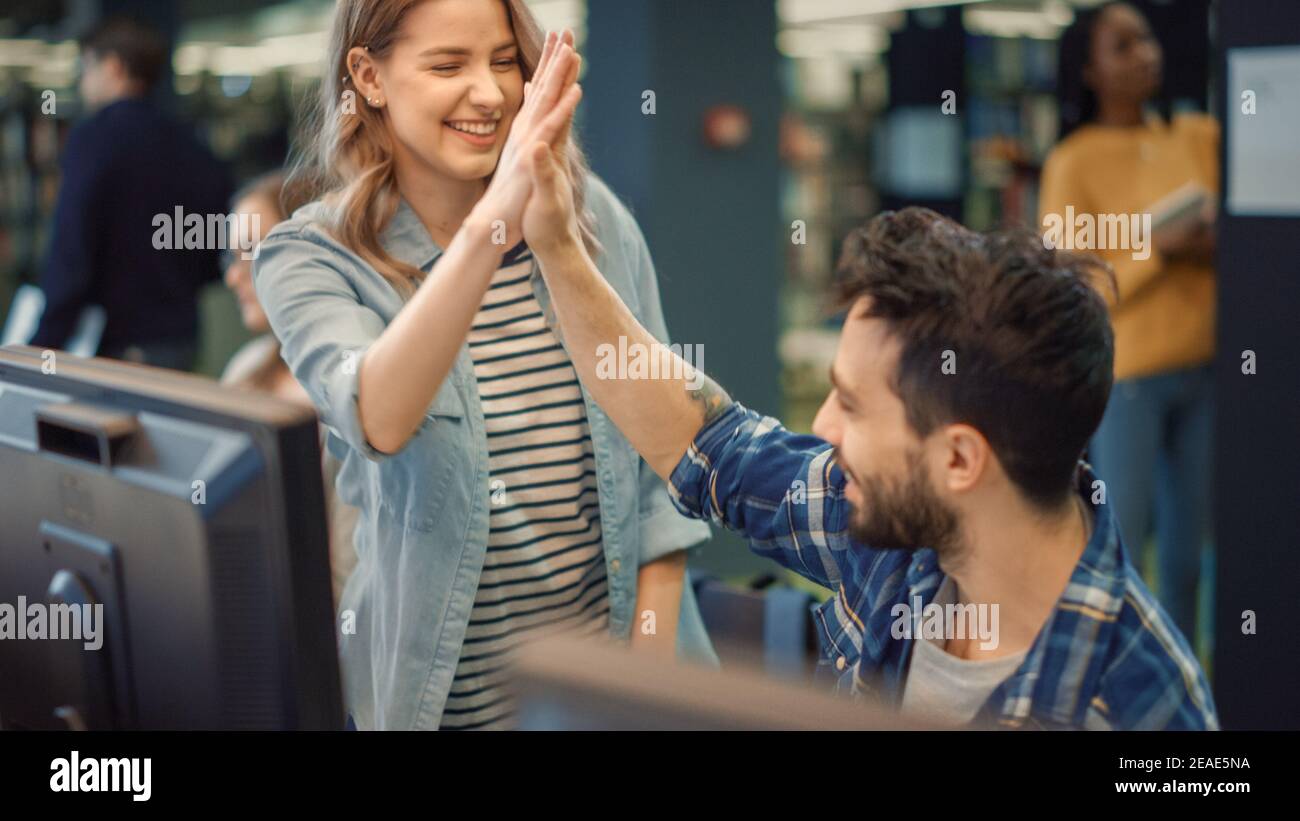 Bibliothèque de l'université : Bright Caucasian Girl and talentueuse Boy Study for Exams and Donnez High Five après une tâche résolue avec succès. Travail sur affectation, utiliser Banque D'Images