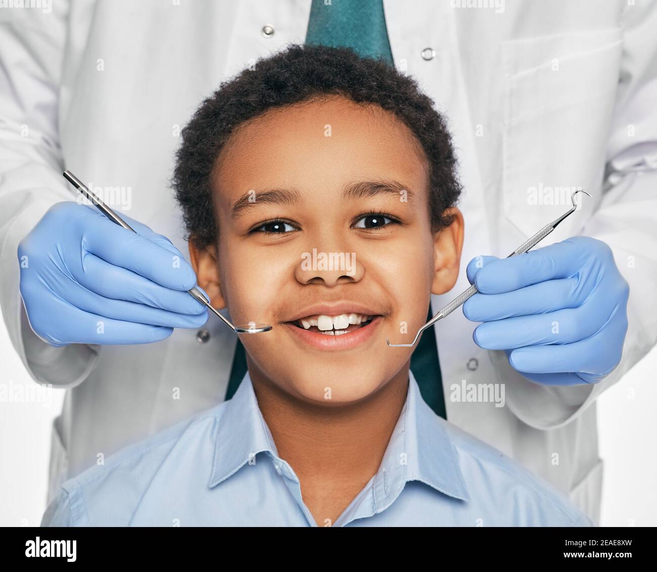 Garçon afro-américain en clinique dentaire pour enfants. Enfant avec un sourire Toothy lors de l'inspection de la cavité buccale par un dentiste. Gros plan Banque D'Images