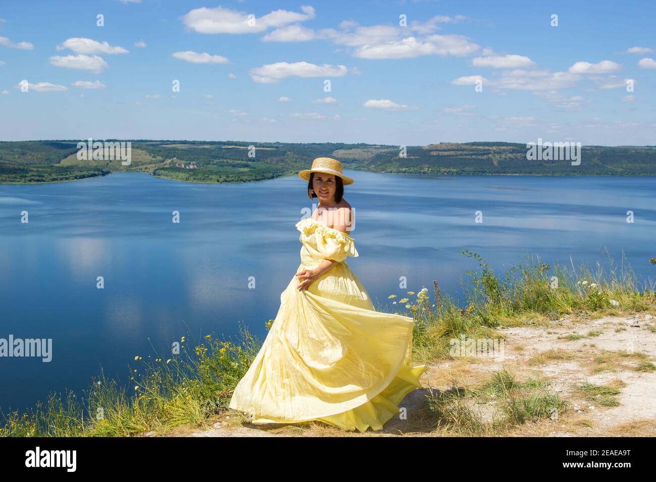 Une fille dans une longue robe dansant sur une falaise par la baie Banque D'Images