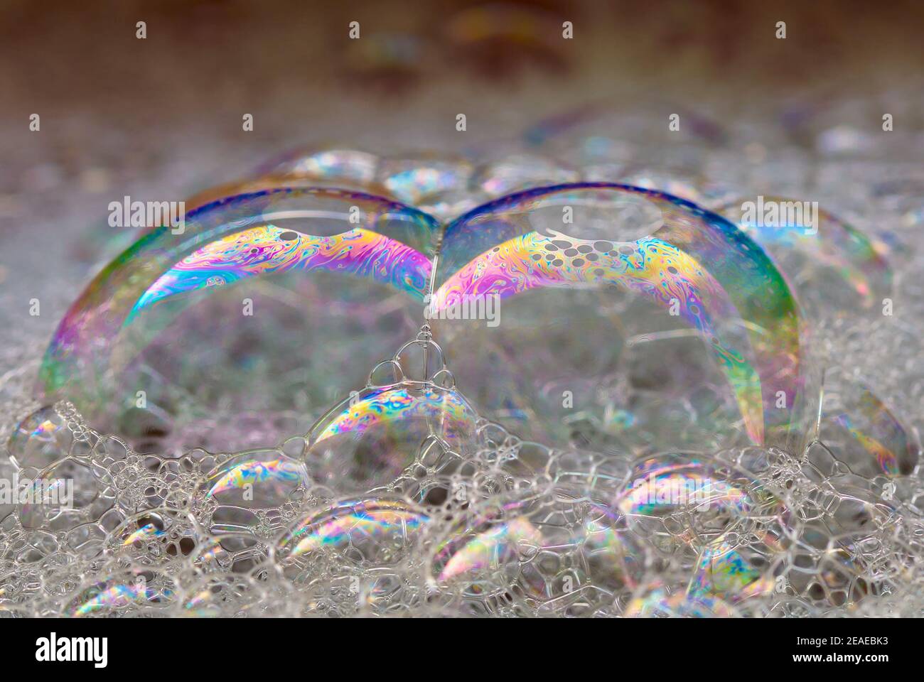 Gros plan de grosses bulles de savon colorées avec un motif arc-en-ciel. Flottant sur l'eau. Arrière-plan abstrait. Banque D'Images