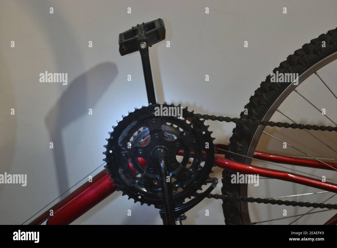 Vélo. Roue dentée, chaîne, pédale, pneu, rayons et partie du cadre d'un vélo rouge pour usage domestique ou sportif, zoom photo, lumière LED bleue avec shado Banque D'Images