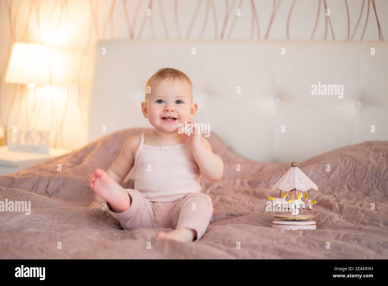 Petite fille mignonne jouant avec des jouets en bois à la chambre à la maison. Intérieur moderne pour bébé de couleur rose Banque D'Images