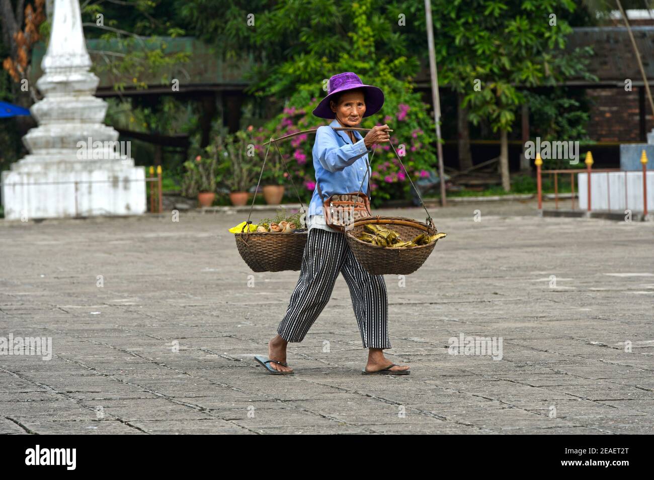 Femme laotienne avec des paniers sur son épaule revenant de shopping dans le marché vert, Luang Prabang, Laos Banque D'Images