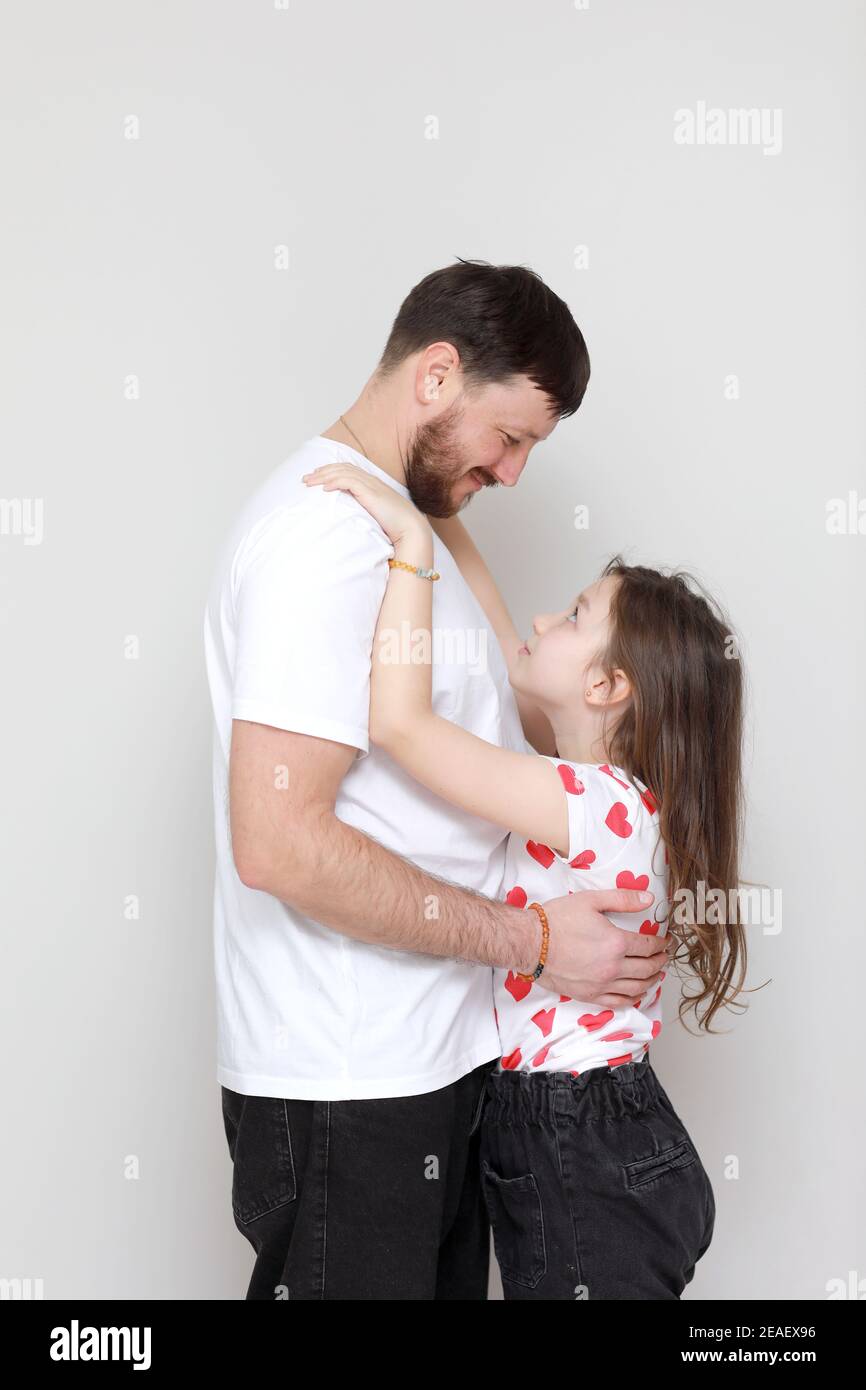 la fête des pères. vue latérale affectueuse petite fille enfant embrasse un père barbu souriant. Bonne petite fille d'enfant appréciant un moment doux avec papa sur W Banque D'Images