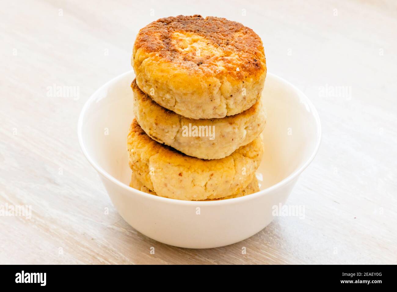 Crêpes maison au fromage syrniki sur un bol rond blanc sur fond de table rustique blanc Banque D'Images