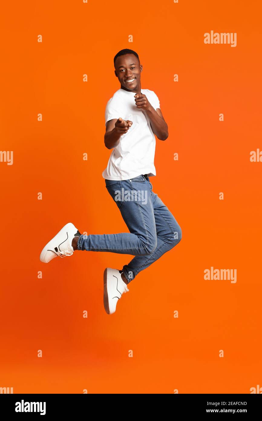 Homme noir charismatique pointant vers l'appareil photo sur l'orange Banque D'Images