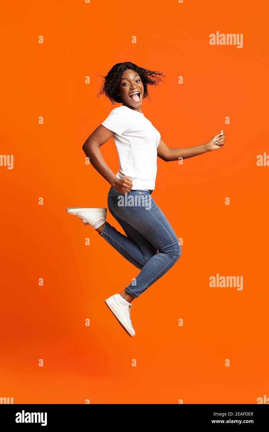 Joyeuse jeune femme noire posant sur l'orange Banque D'Images