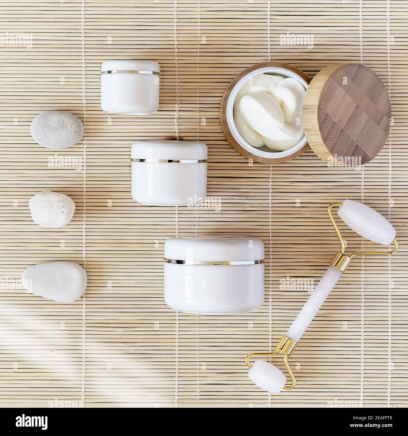 Flat Lay avec des pots de cosmétiques à la crème, des pierres et un rouleau de massage facial sur fond naturel mat. Maquette de produit de beauté naturel Banque D'Images