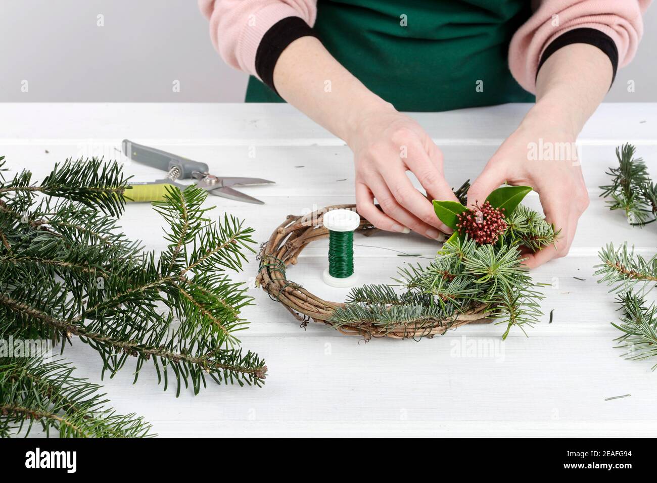 Fleuriste au travail: Femme montre comment faire la couronne de porte de Noël faite de branches de sapin. Étape par étape, tutoriel. Banque D'Images