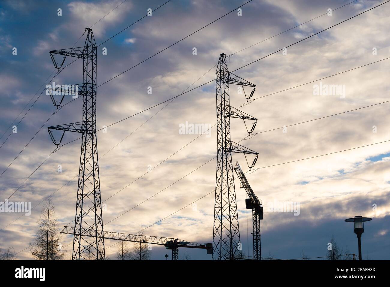 Une grande machine de construction sur un chantier de construction pendant le soleil couchant. Grue fixe basée sur une barre. Ligne haute tension. Banque D'Images