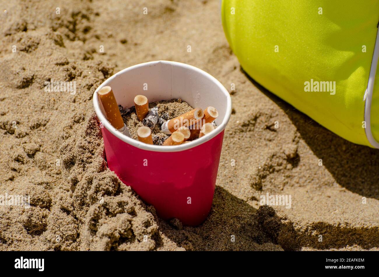 Cigarettes non allumées dans un verre à plomb sur la plage Banque D'Images