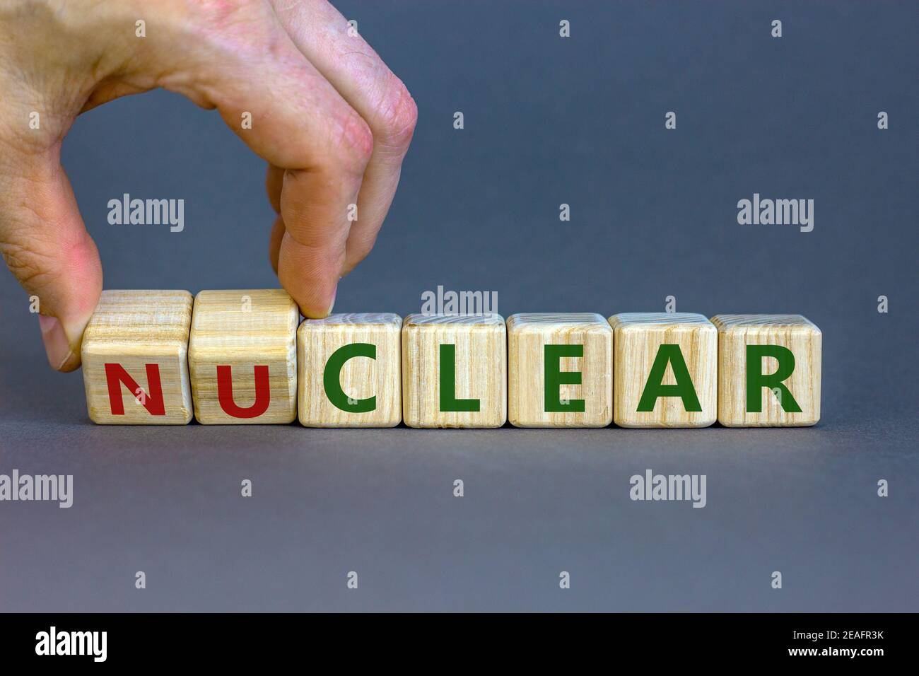 Symbole nucléaire ou clair. Homme d'affaires transforme un cube et transforme le mot « nucléaire » en « clair ». Magnifique fond gris. Nucléaire ou clair et affaires Banque D'Images