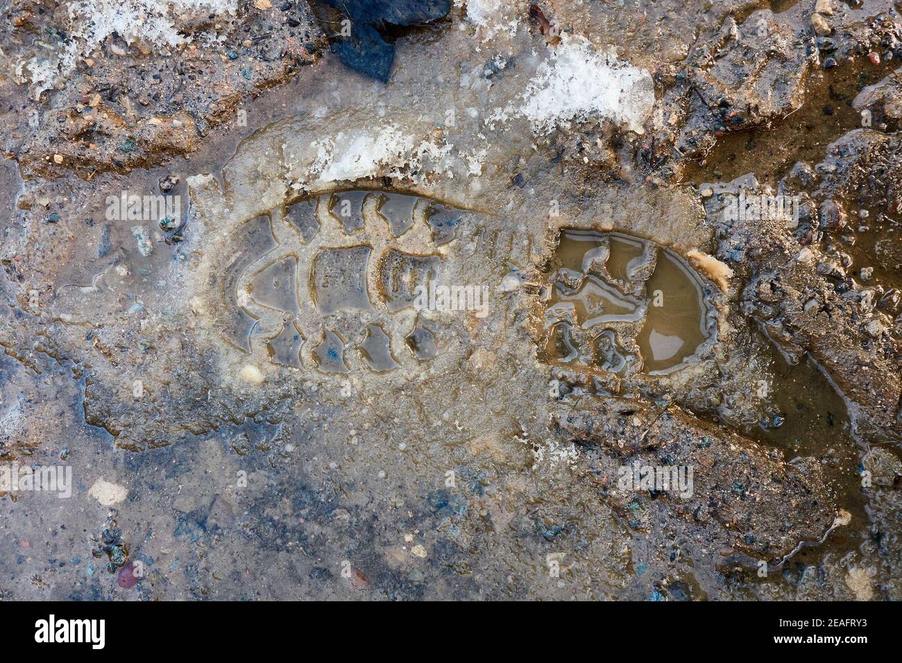 Empreinte droite unique d'une botte faite dans la neige tassée et boue Banque D'Images