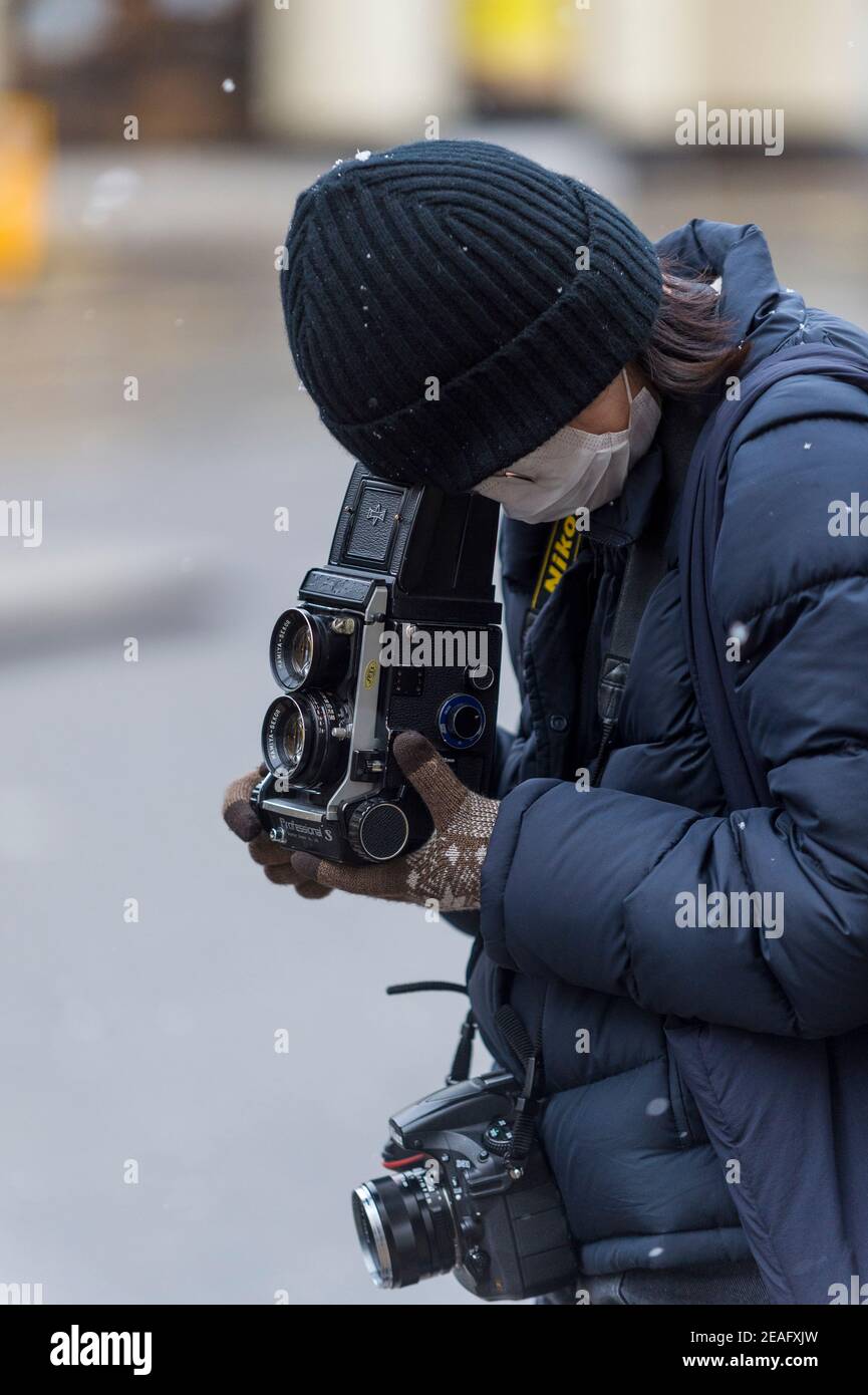 Londres, Royaume-Uni. 9 février 2021. Météo au Royaume-Uni : un photographe portant un masque facial prend une photo avec un appareil photo de format moyen Mamiya alors que la pandémie de coronavrius continue, à l'extérieur et sur le Strand pendant les averses de neige légères comme le temps froid provoqué par Storm Darcy continue. Credit: Stephen Chung / Alamy Live News Banque D'Images