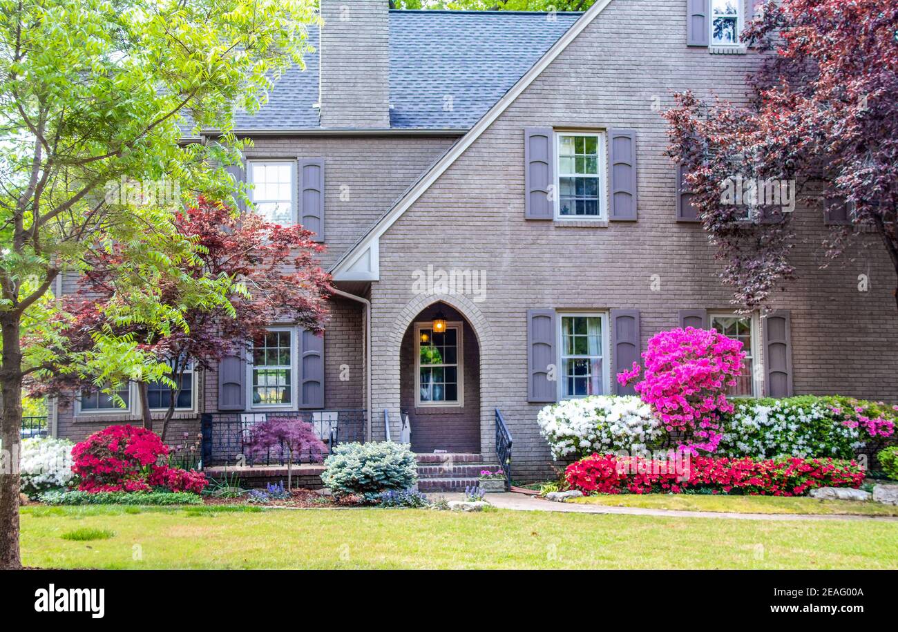 Entrée à la maison de deux étages en briques grises paysagée avec des japonais Les mauves et les azalées sont dotées de volets et d''un coin salon à l''avant Banque D'Images