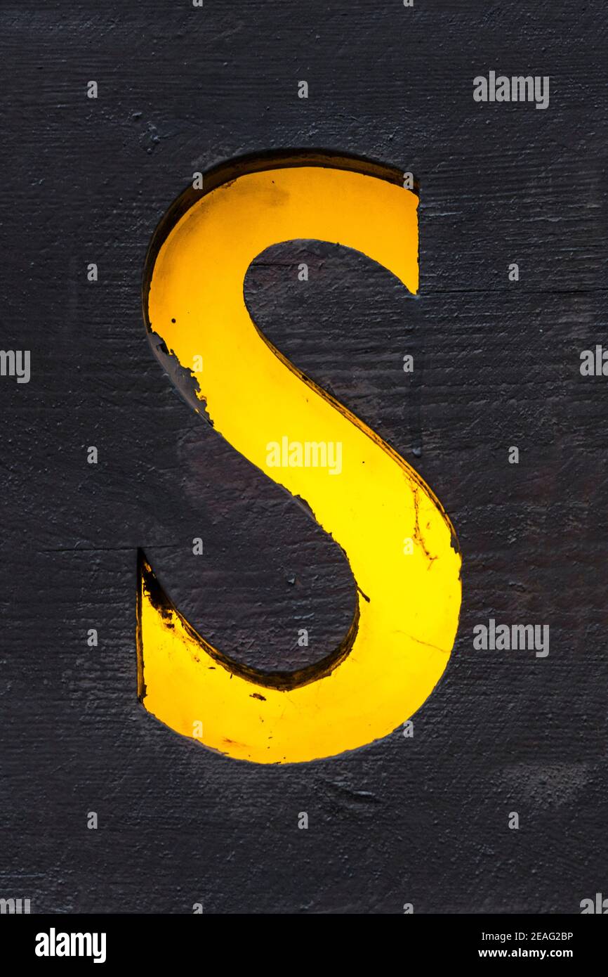 Lettre rétro-éclairée jaune A scié hors d'une planche en bois Banque D'Images