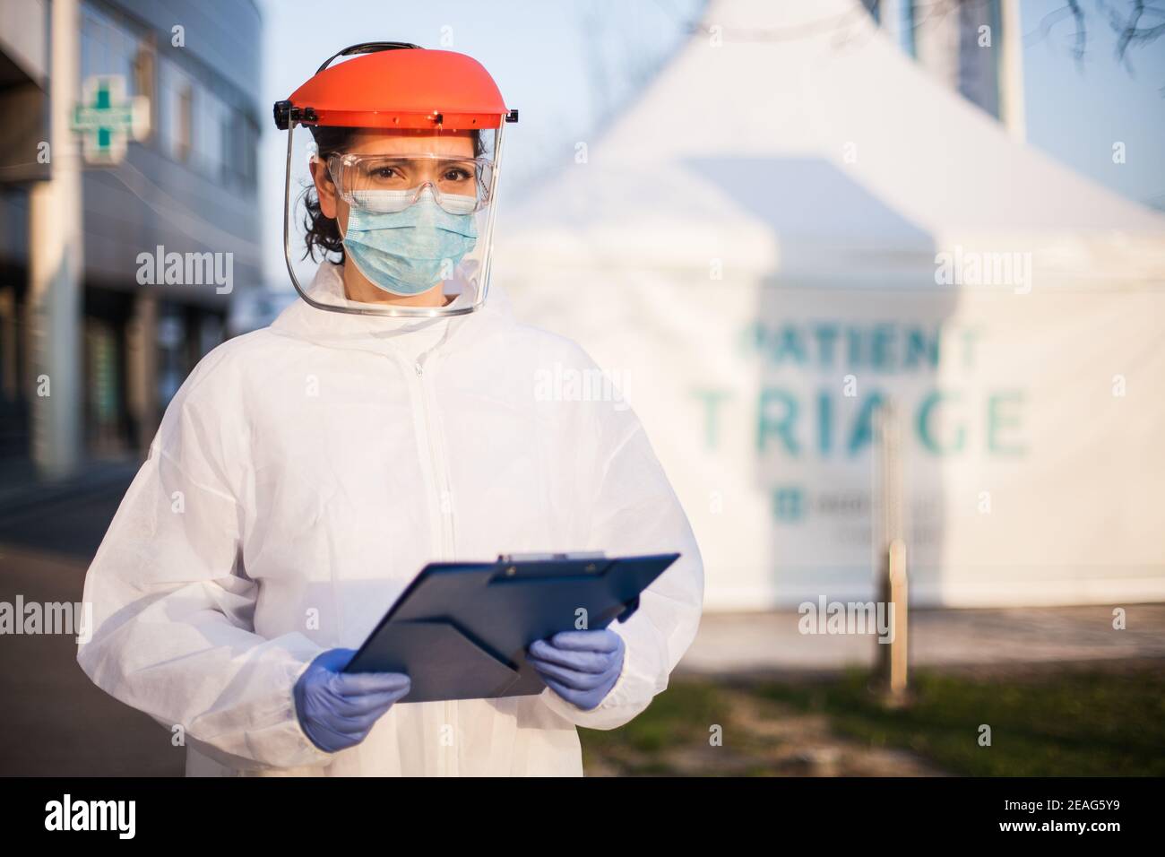 Inquiet épuisé et stressé, le médecin britannique du NHS de Frontline, portant des EPI et Écran facial, hors de l'hôpital patient triage tente quarantaine, US COVID-19 spécial po Banque D'Images