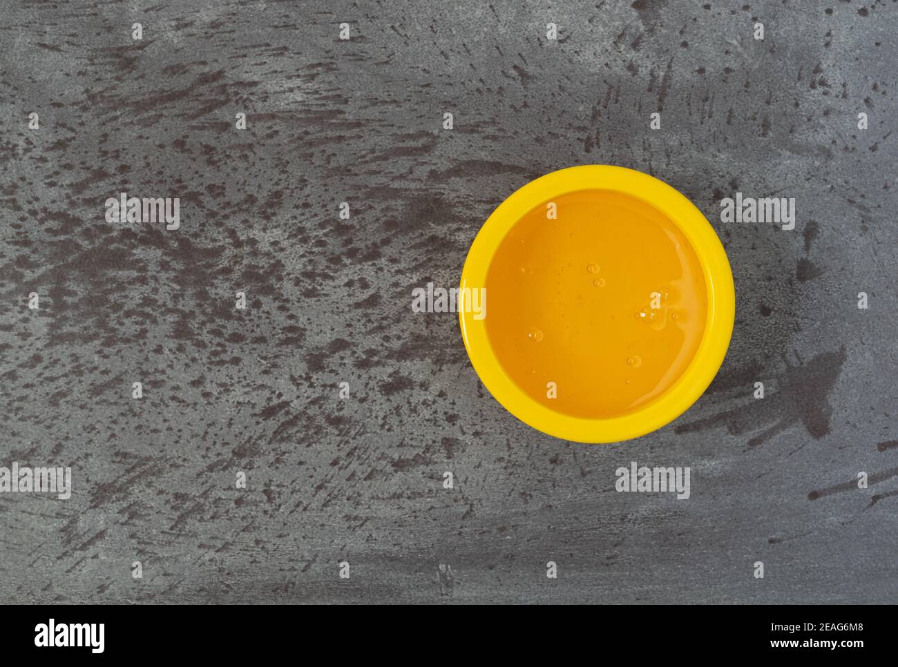 Bol jaune de sirop de maïs léger décalé sur fond gris éclairé par un éclairage naturel. Banque D'Images