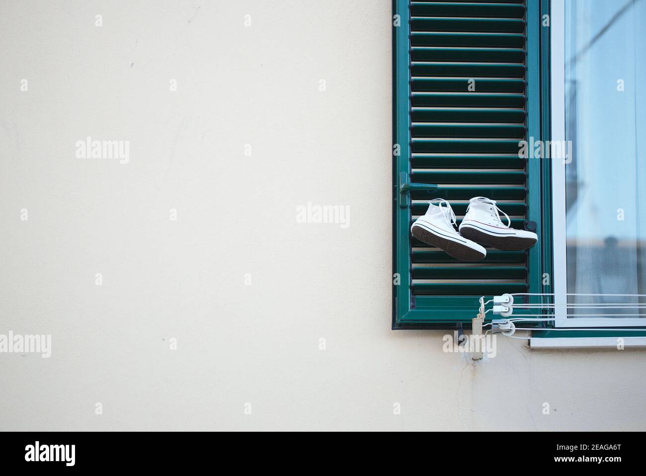 Le cadre avec une paire de sneakers en toile et un espace de copie pour votre texte. Soft focus.Canvas Shoe suspendu à la fenêtre d'une maison typiquement italienne. Concep Banque D'Images