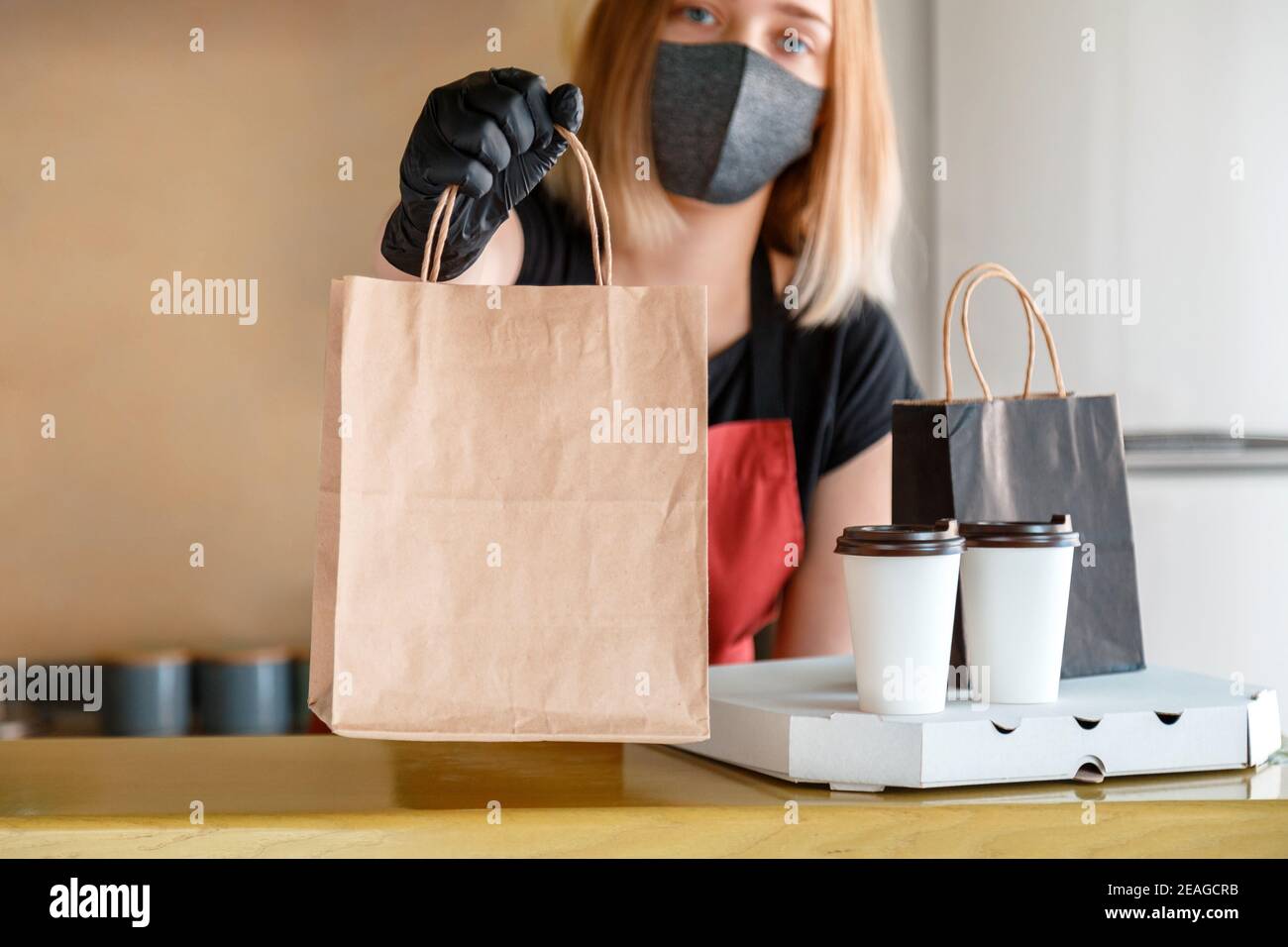 Sac alimentaire, pizza, forfait boisson à emporter au restaurant à emporter. Le travailleur de cuisine émet des commandes en ligne dans des gants et un masque. Maquette de sac en papier à emporter Banque D'Images