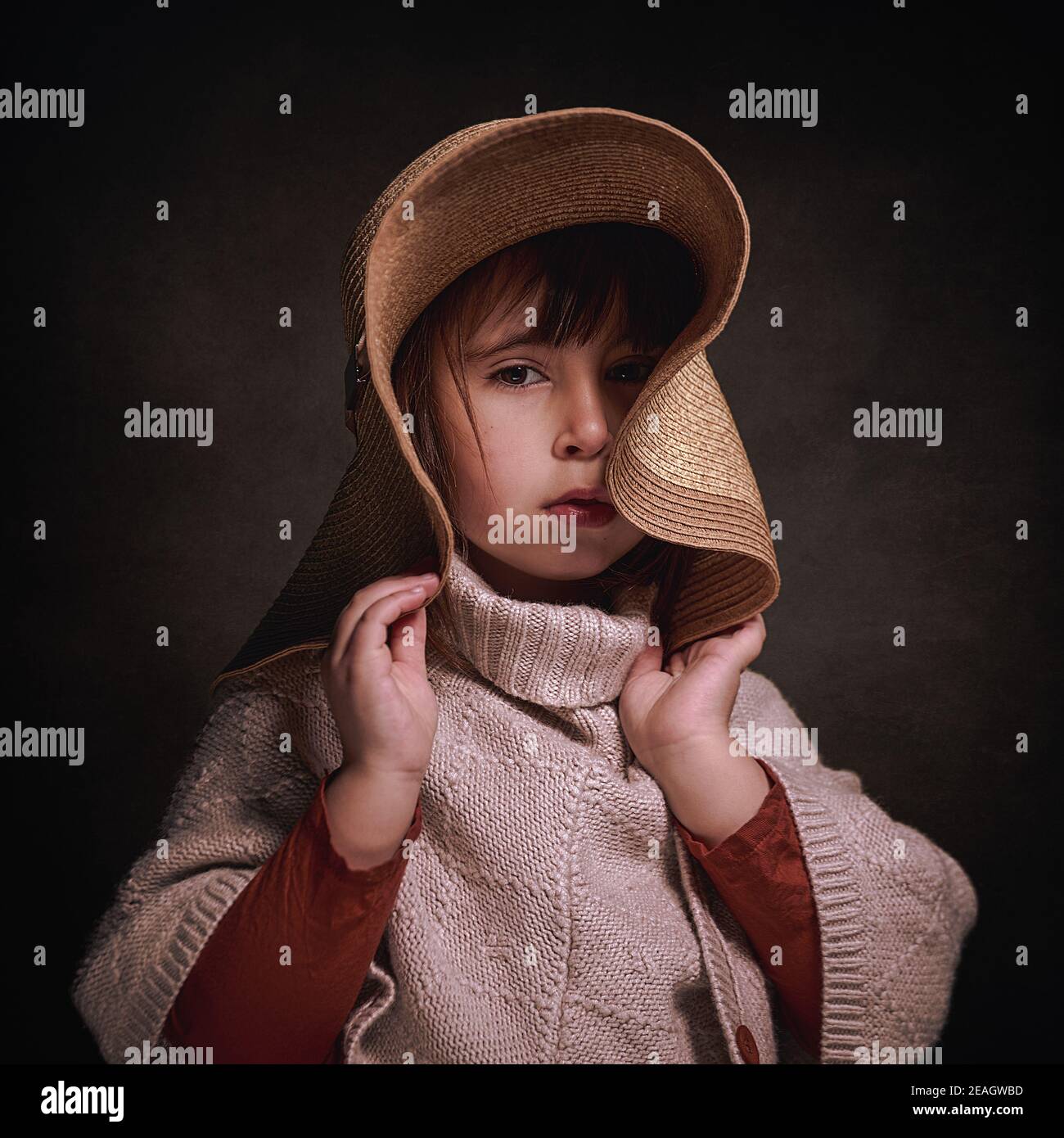 Fille caucasienne de 4 ans avec chapeau et poncho en tissu. Elle pose élégante et élégante en tenant le chapeau avec ses mains. Banque D'Images