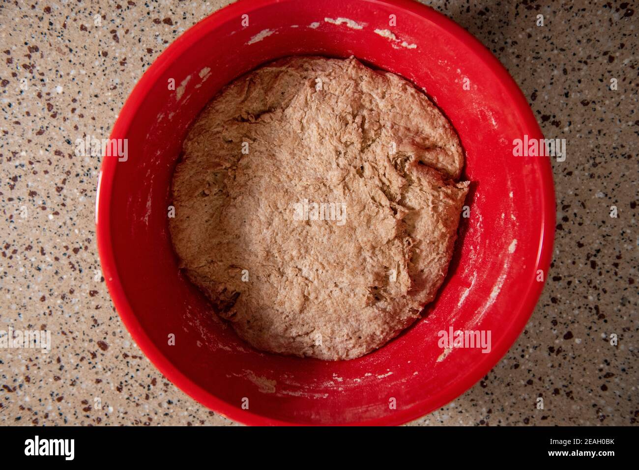 Une boule de pâte à pain dans un saladier rouge découvert après quelques heures de lever. Série étape par étape pour faire du pain maison. Cadre 7 de 13 Banque D'Images