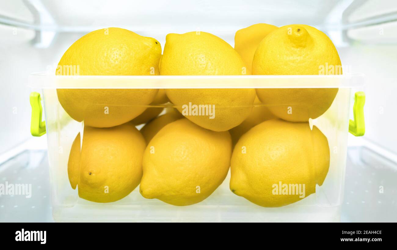 Réfrigérateur au citron, limonade, détox, jus de fruits mûrs dans un réfrigérateur en plastique. Récipients de stockage de nourriture citrons réfrigérateur saine alimentation fruits frais Banque D'Images