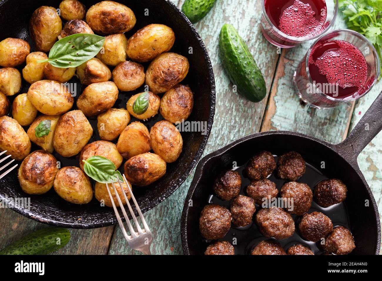 Cuisine scandinave. Pommes de terre frites, boulettes de viande et boisson aux baies de lingonberry servies avec des légumes et des herbes sur une table bleue rustique avec vue au plafond Banque D'Images