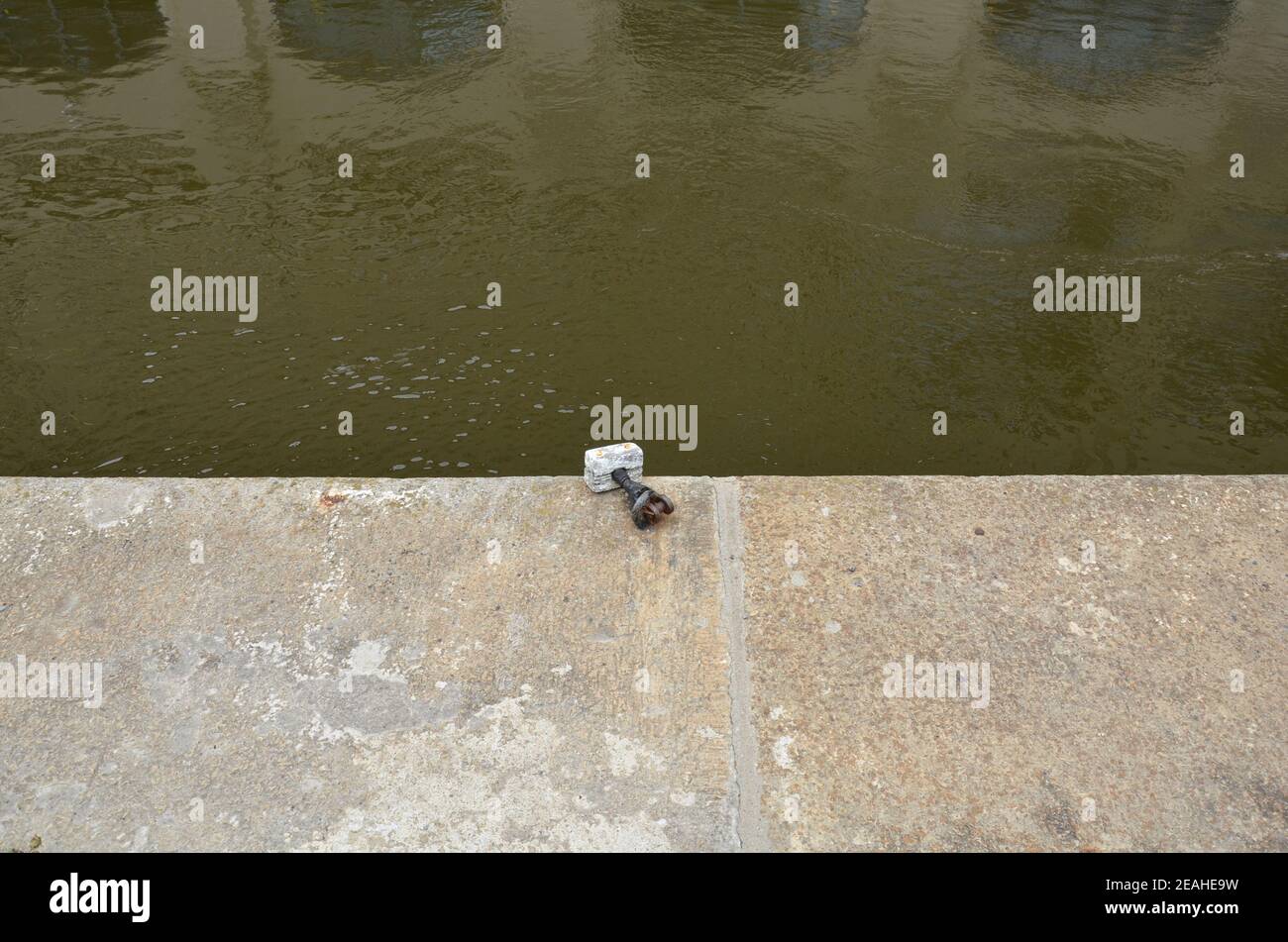 eau trouble dans la rivière ou le canal avec attache de bateau et trottoir Banque D'Images