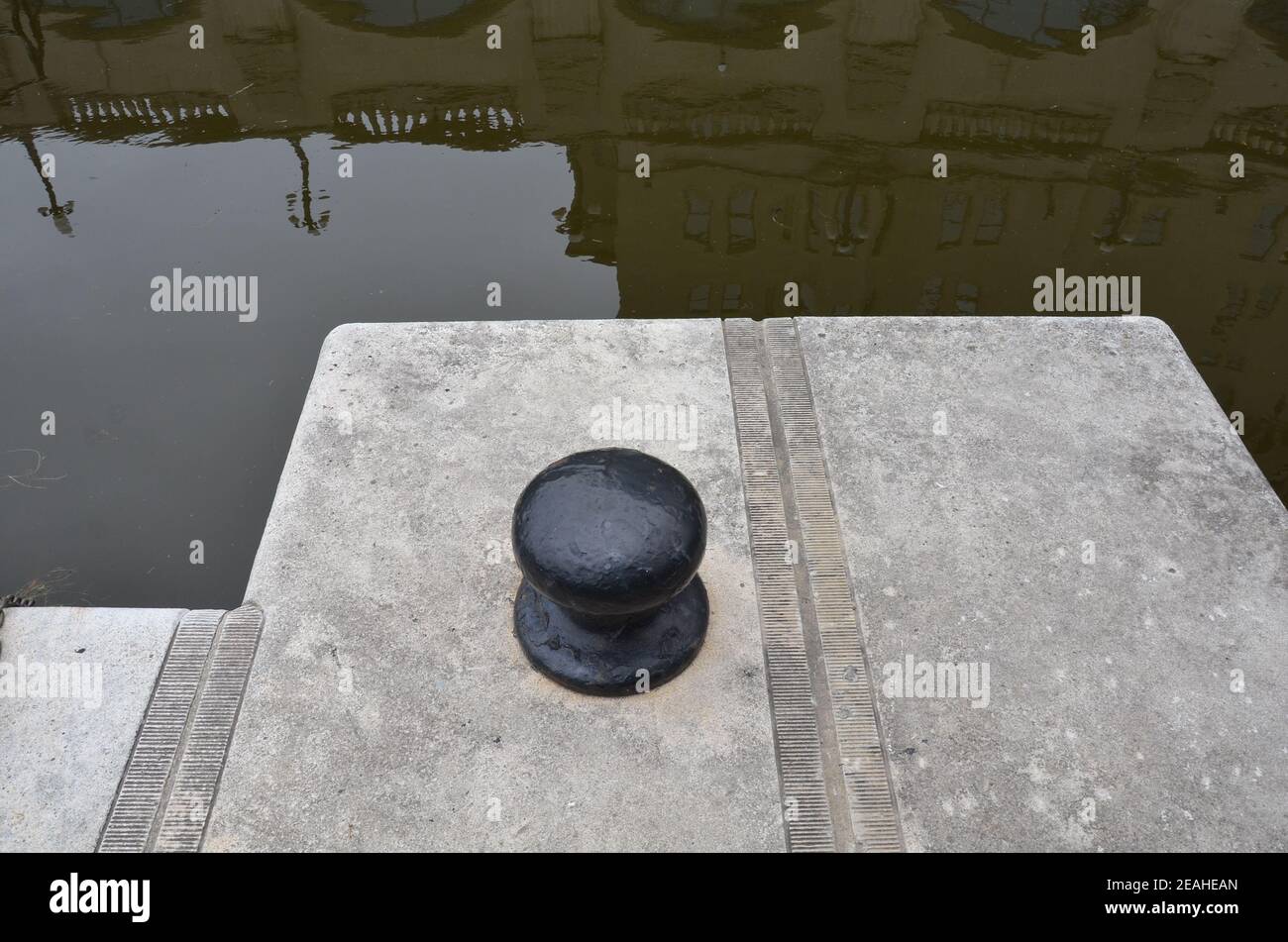 eau trouble dans la rivière ou le canal avec attache de bateau et trottoir Banque D'Images