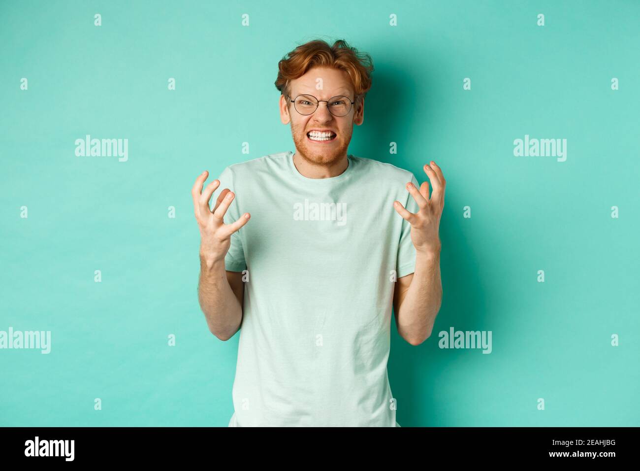 Portrait d'un homme à tête rouge en colère et en détresse qui perdait du tempérament, criant et secouant les mains indignées, regardant avec le visage furieux à l'appareil photo, debout Banque D'Images