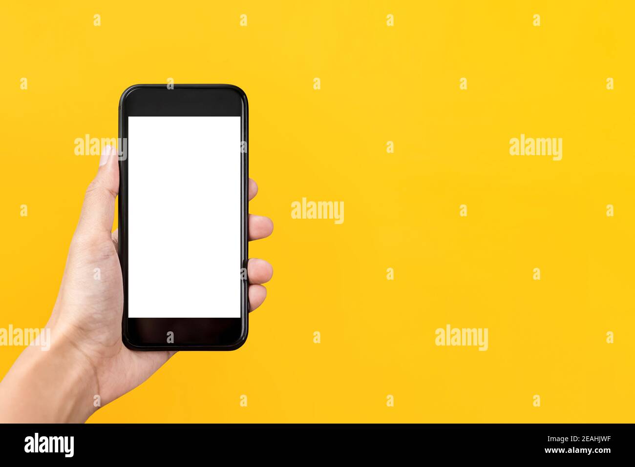 Main tenant un écran vide téléphone portable isolé sur fond jaune avec espace de copie Banque D'Images