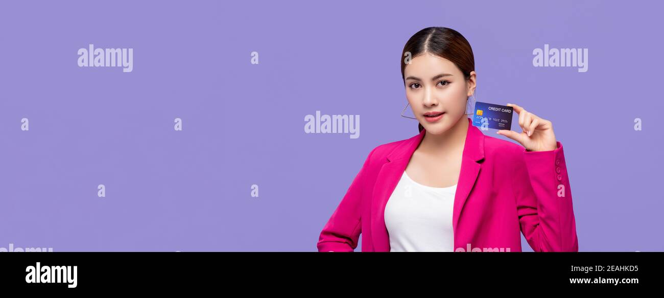 Belle femme asiatique montrant la carte de crédit à la main pour des finances et les concepts de société sans espèces sur fond de bannière violet avec copie espace Banque D'Images