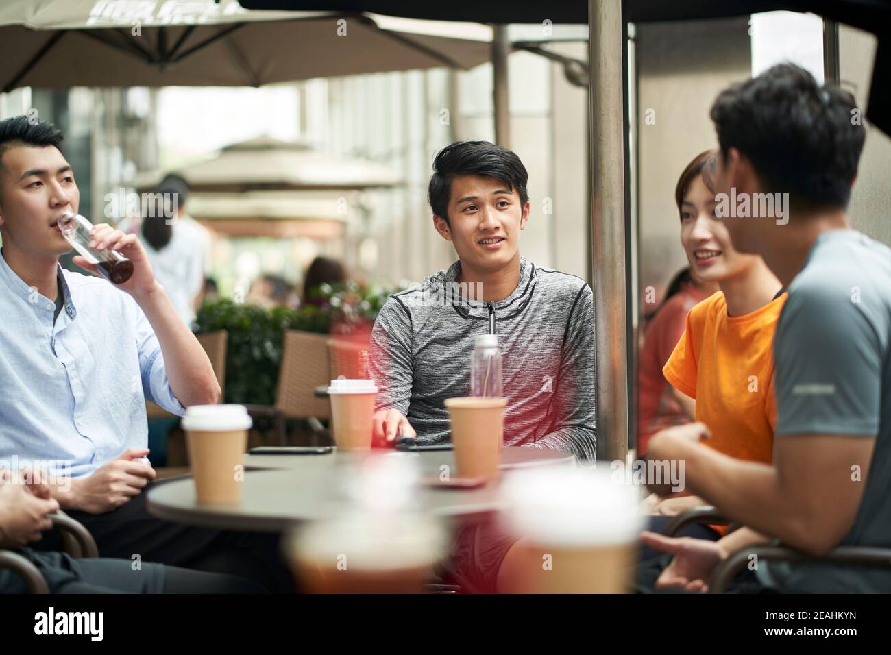 jeunes adultes asiatiques, hommes et femmes, bavardant en se détendant café-restaurant extérieur Banque D'Images