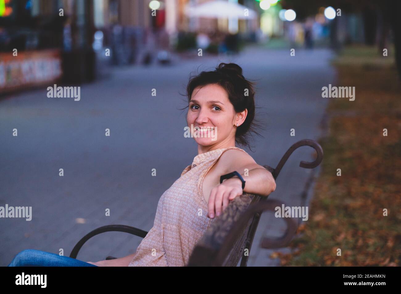 Portrait d'une jeune femme souriante. Femme européenne élégante assise sur le banc. Portrait extérieur d'une fille blanche incroyable Banque D'Images