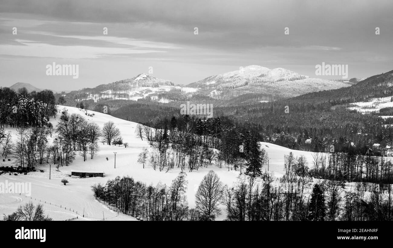 Neige hiver paysage vallonné. Belle gamme rurale. Panorama avec le village de Kytlice dans les montagnes de Lusatien, République tchèque. Image en noir et blanc. Banque D'Images