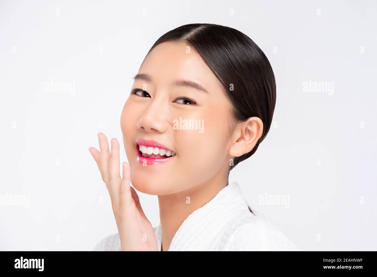 Jeune femme asiatique souriant à la main, touchant le visage fond blanc pour les concepts de beauté et de soins de la peau Banque D'Images
