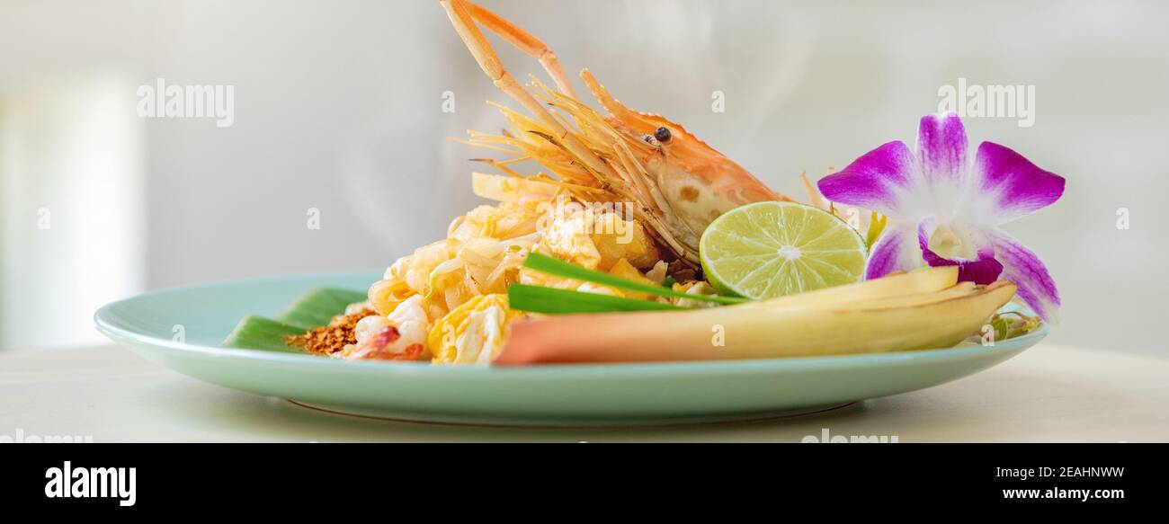 Délicieux plats asiatiques, plat de nouilles thaï chaud aux crevettes fraîches sur le fond de la bannière de la table de cuisine Banque D'Images