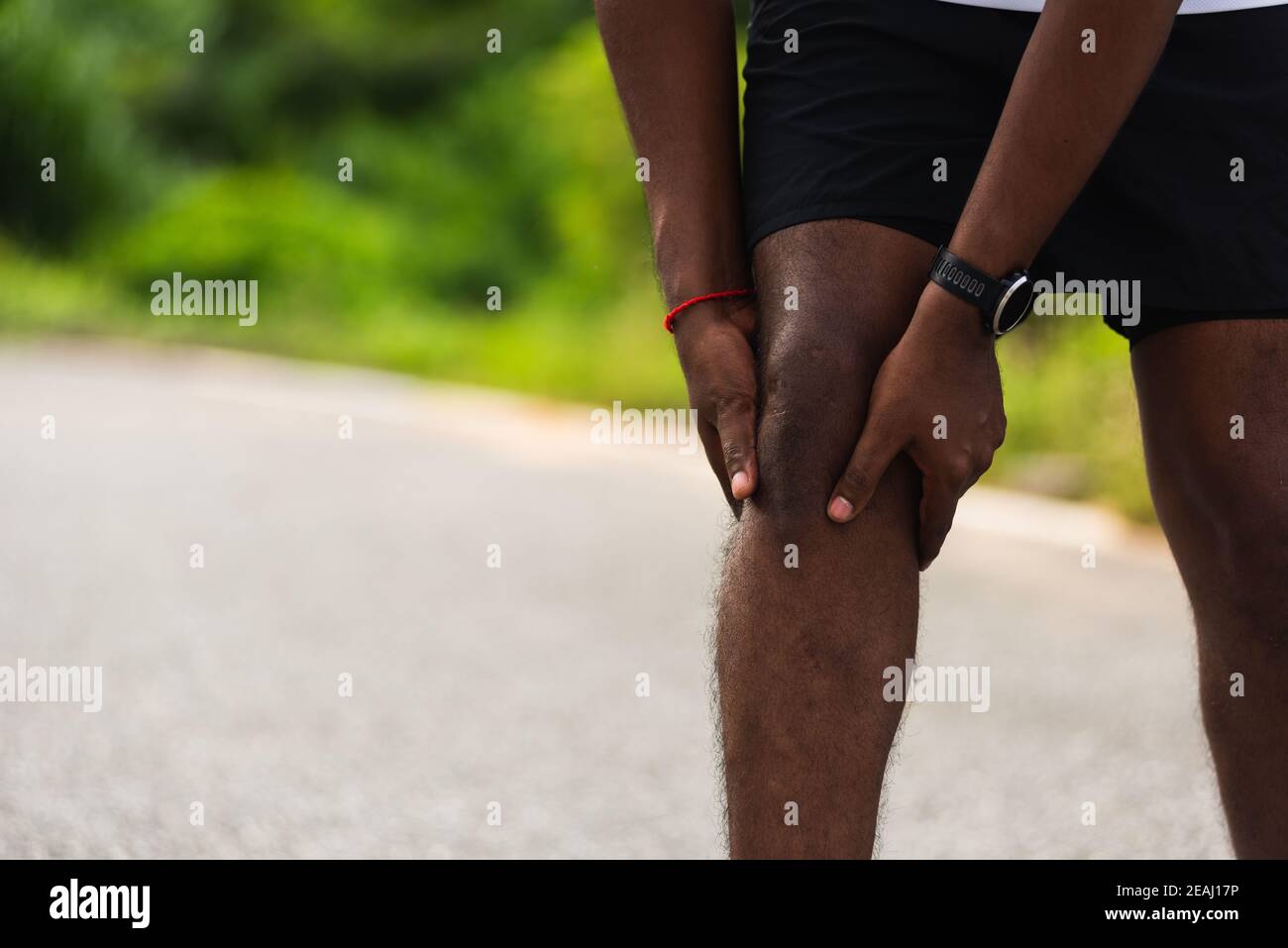 sport coureur noir homme porter montre mains joint tenir genou la douleur Banque D'Images